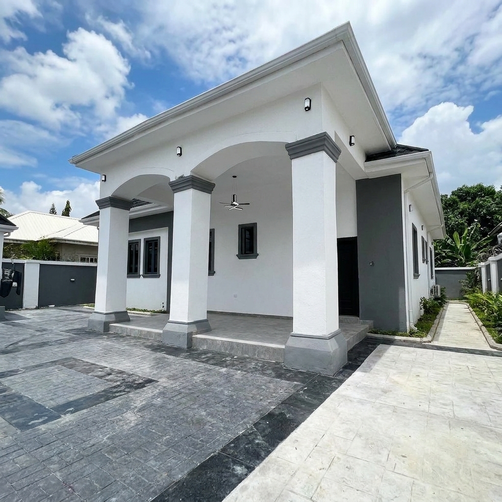 Front view of a modern white single-story house with dark grey pillars, a spacious covered porch, and a wide stamped concrete driveway.