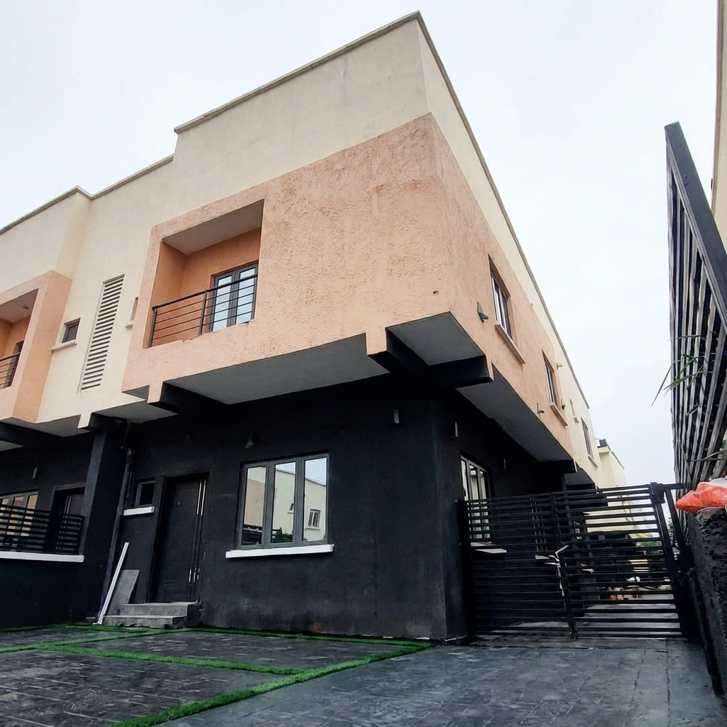 Exterior view of a modern two-story townhouse featuring a black ground floor, peach upper level, and a paved driveway with grass strip accents.